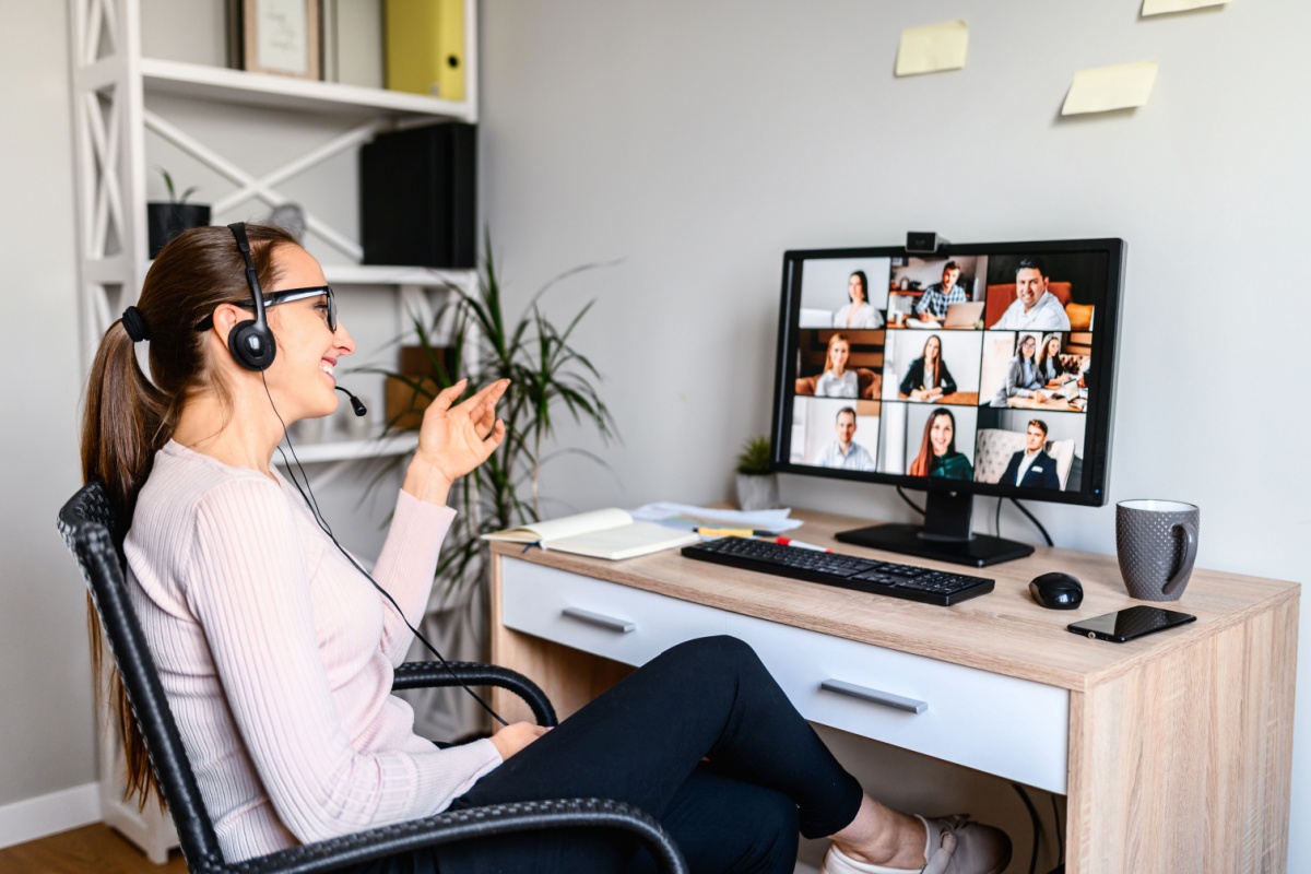 Woman on headset talking in conference call on computer.